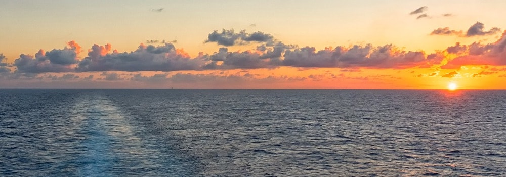 Fahrt mit einem Kreuzfahrtschiff bei Sonnenuntergang mit Blick auf das Meer vom Heck aus